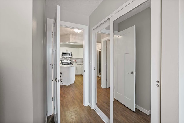 corridor with dark hardwood / wood-style floors and a textured ceiling