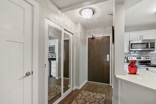 doorway with a textured ceiling and dark hardwood / wood-style floors