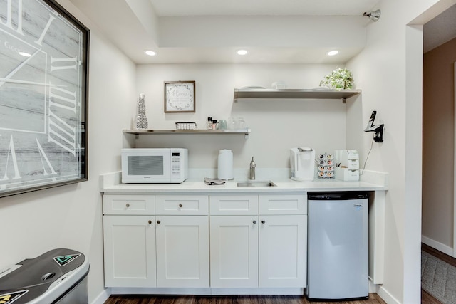 bar featuring stainless steel dishwasher, sink, white cabinets, and dark hardwood / wood-style flooring