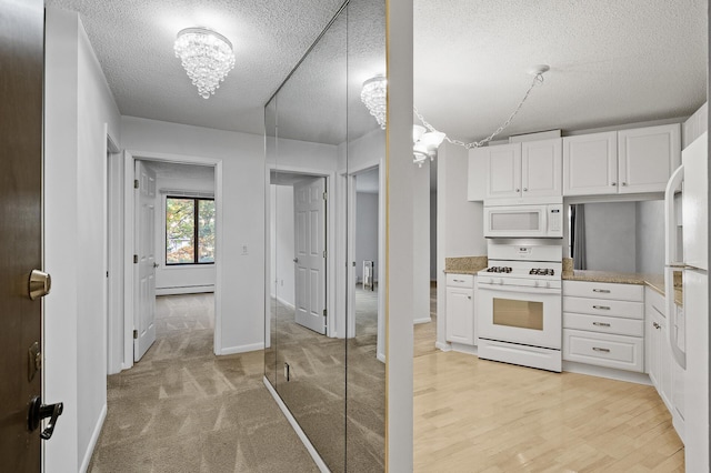 kitchen featuring white cabinetry, light wood-type flooring, a textured ceiling, and white appliances