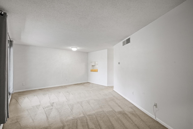 carpeted empty room featuring a textured ceiling