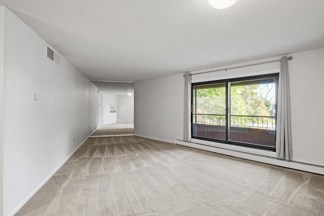 carpeted spare room featuring a textured ceiling and a baseboard heating unit