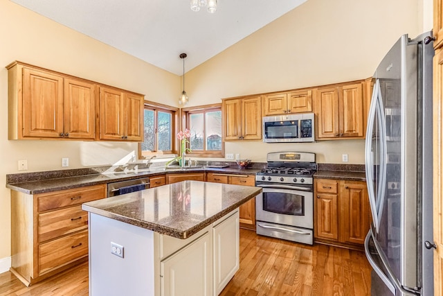 kitchen featuring stainless steel appliances, a center island, light wood-type flooring, and hanging light fixtures