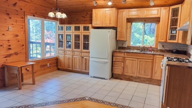 kitchen with light tile patterned flooring, dark countertops, a sink, white appliances, and tasteful backsplash