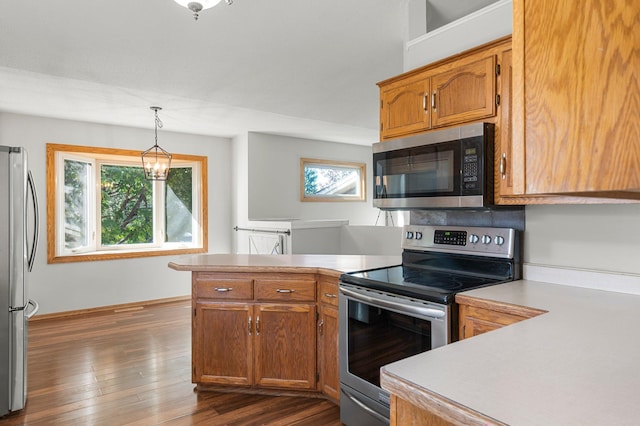 kitchen featuring stainless steel appliances, dark hardwood / wood-style flooring, kitchen peninsula, pendant lighting, and a notable chandelier