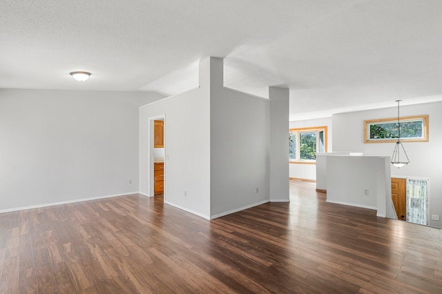 unfurnished room with a textured ceiling, vaulted ceiling, and dark hardwood / wood-style flooring