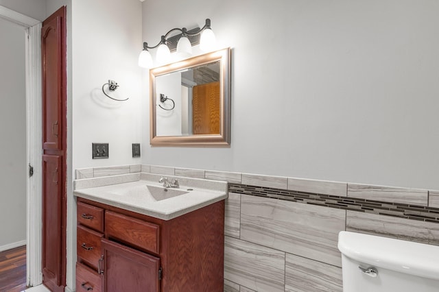 bathroom with wood-type flooring, vanity, tile walls, and toilet