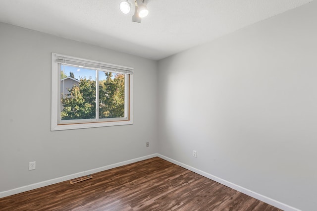 unfurnished room featuring dark hardwood / wood-style flooring and a textured ceiling