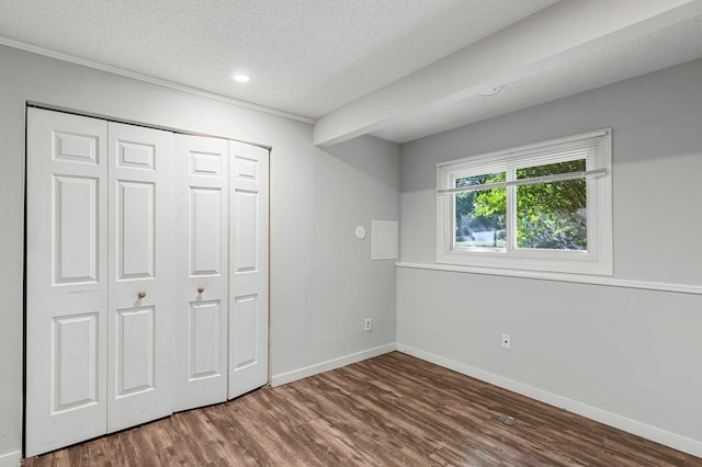 unfurnished bedroom featuring beam ceiling, a closet, dark hardwood / wood-style floors, and a textured ceiling