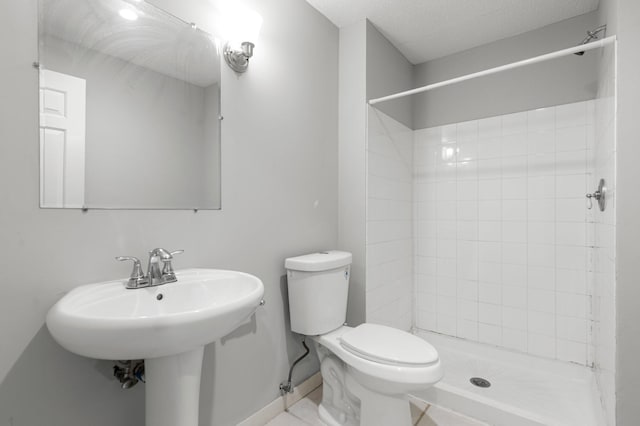 bathroom featuring a tile shower, toilet, and a textured ceiling