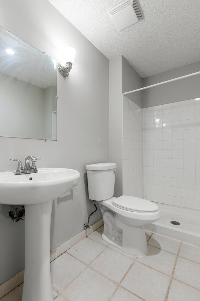 bathroom featuring tile patterned flooring, a tile shower, and toilet