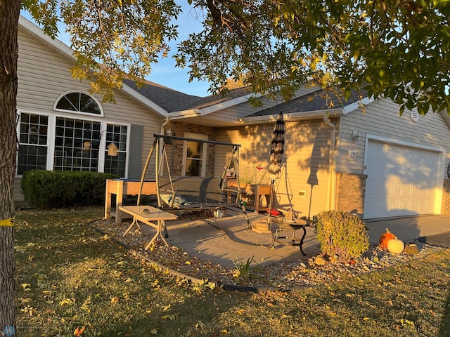 back of property featuring a yard, a garage, and a patio area