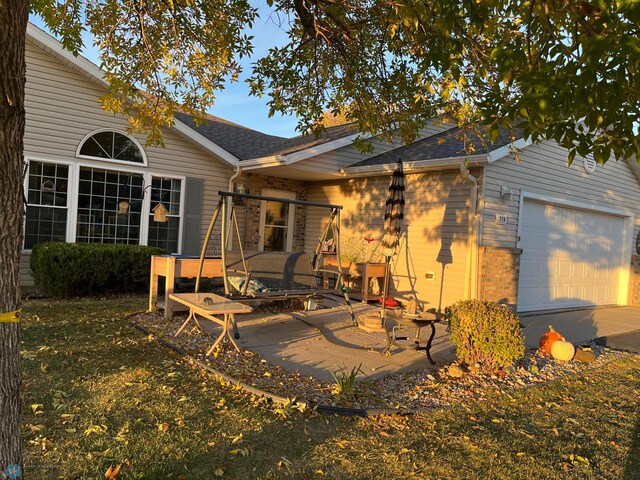 358 30th St N, Moorhead, MN 56560 - rear view of property featuring a shingled roof, a patio area, brick siding, and a garage