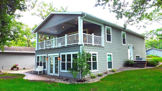 rear view of house featuring a patio, a balcony, and a lawn