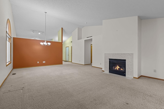 unfurnished living room with carpet flooring, a tile fireplace, an inviting chandelier, high vaulted ceiling, and track lighting