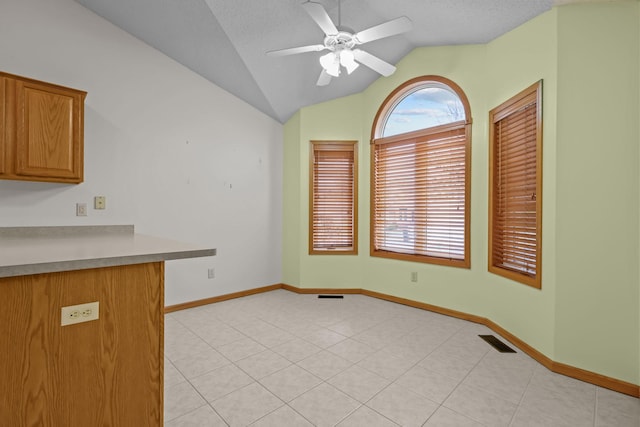 unfurnished dining area featuring a textured ceiling, ceiling fan, light tile patterned floors, and vaulted ceiling