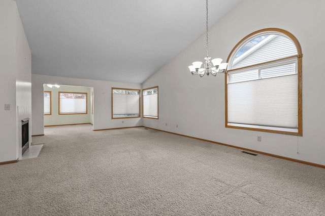 carpeted empty room with high vaulted ceiling and a chandelier