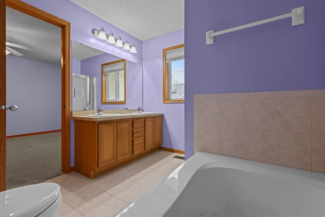 bathroom featuring tile patterned floors, a textured ceiling, a tub to relax in, and toilet