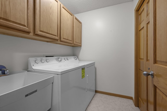 washroom with washer and clothes dryer, cabinets, sink, light tile patterned floors, and a textured ceiling