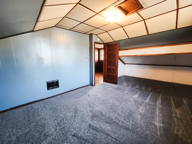 additional living space featuring vaulted ceiling and dark colored carpet