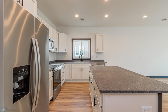 kitchen with a kitchen island, light wood-type flooring, white cabinets, sink, and appliances with stainless steel finishes