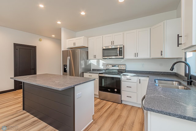 kitchen with sink, white cabinetry, appliances with stainless steel finishes, a center island, and light wood-type flooring