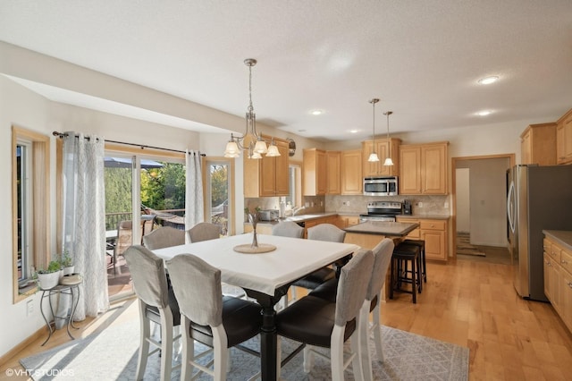 dining space with a chandelier, light hardwood / wood-style floors, and a textured ceiling