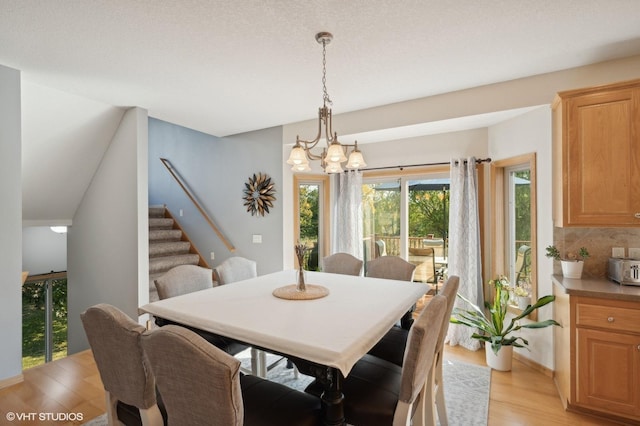 dining space featuring a textured ceiling, a notable chandelier, and light wood-type flooring