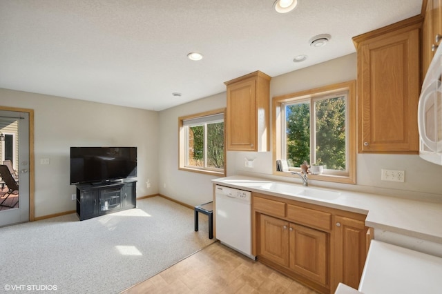 kitchen with light carpet, white dishwasher, and sink