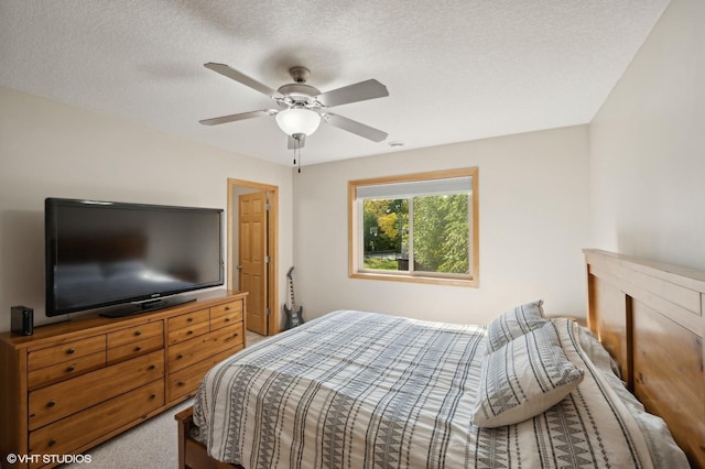 bedroom with ceiling fan, carpet floors, and a textured ceiling