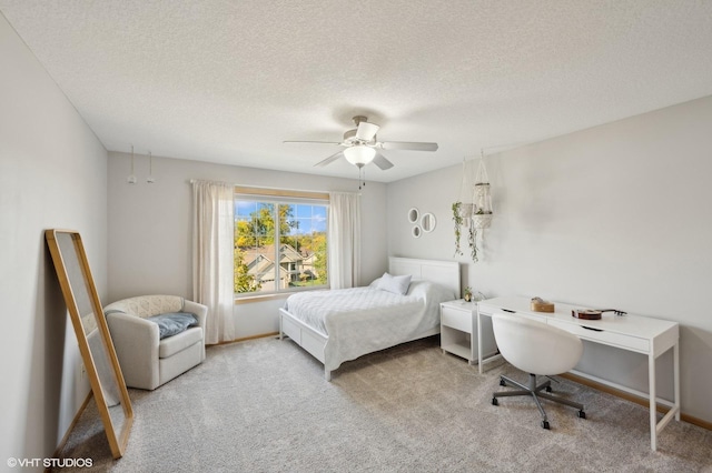 bedroom with ceiling fan, light colored carpet, and a textured ceiling