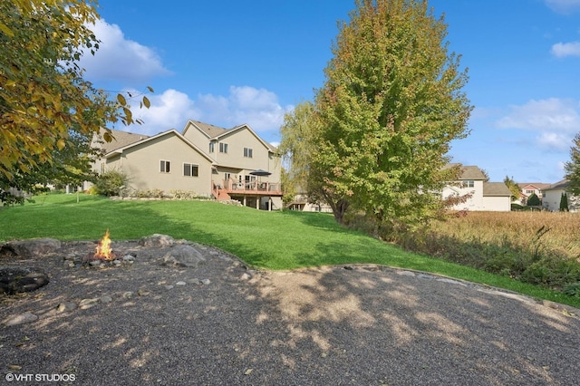 view of yard featuring a wooden deck and a fire pit