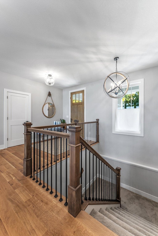 stairway featuring an inviting chandelier, hardwood / wood-style floors, and a textured ceiling