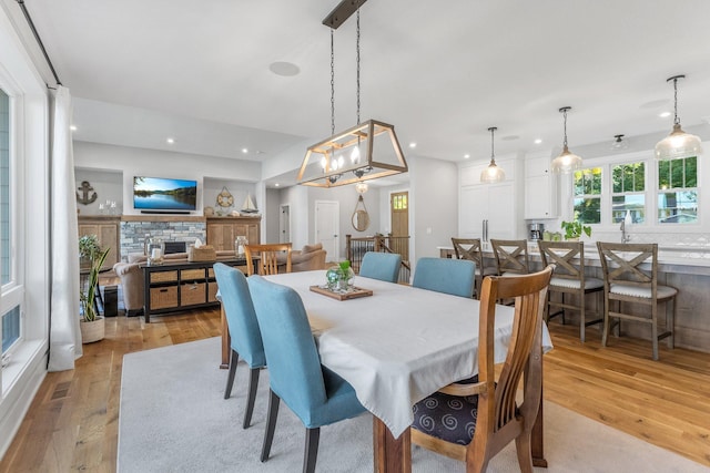 dining room with a stone fireplace and light hardwood / wood-style flooring