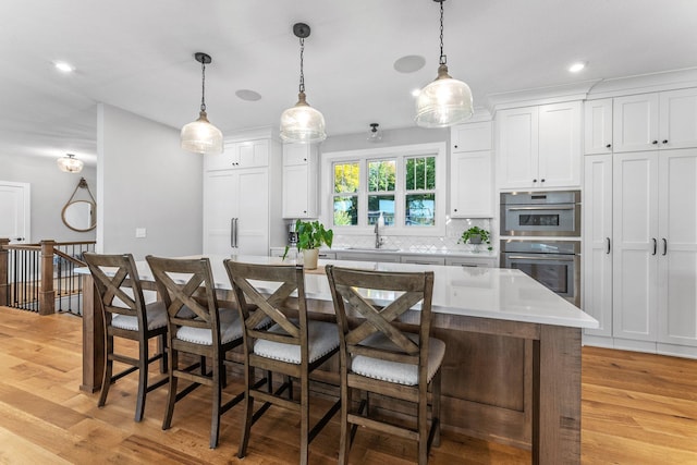 kitchen featuring white cabinets, a breakfast bar area, light hardwood / wood-style flooring, and a center island