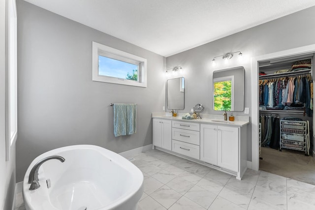 bathroom featuring a tub to relax in, vanity, and a textured ceiling