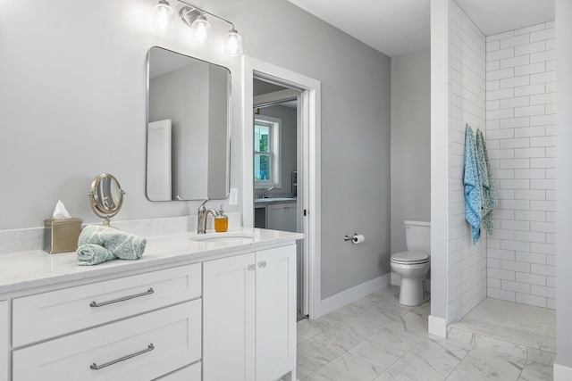 bathroom with a tile shower, vanity, and toilet