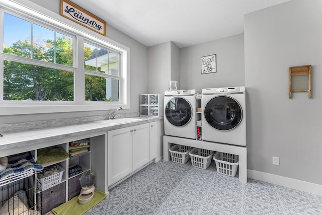 laundry area with separate washer and dryer, cabinets, and sink