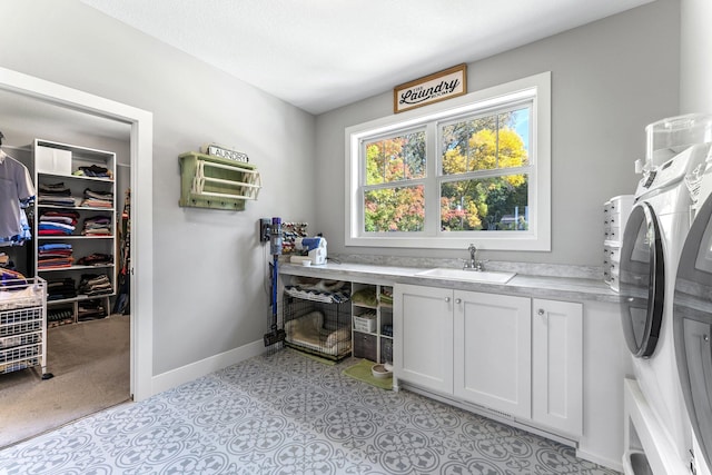 laundry area with washing machine and clothes dryer, cabinets, and sink