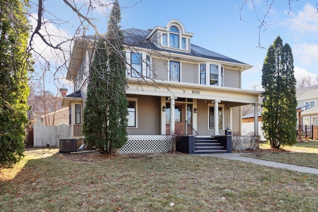 view of front of property with covered porch, a front yard, and central AC