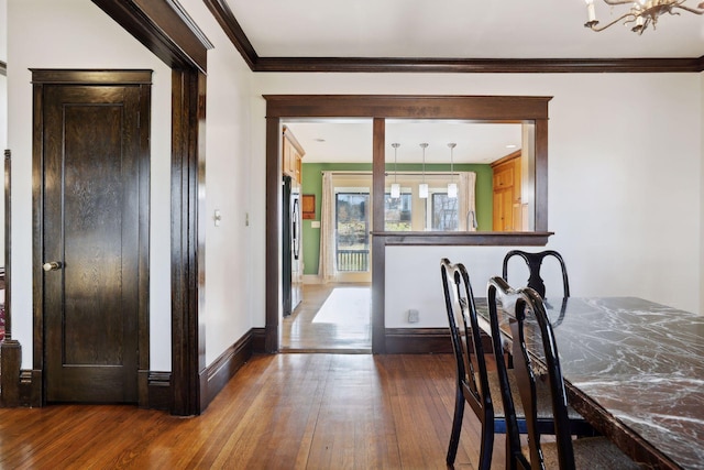 dining area with hardwood / wood-style flooring, a notable chandelier, and ornamental molding