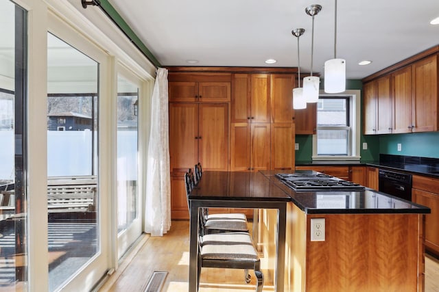 kitchen with light wood-type flooring, stainless steel gas cooktop, dishwasher, a center island, and hanging light fixtures