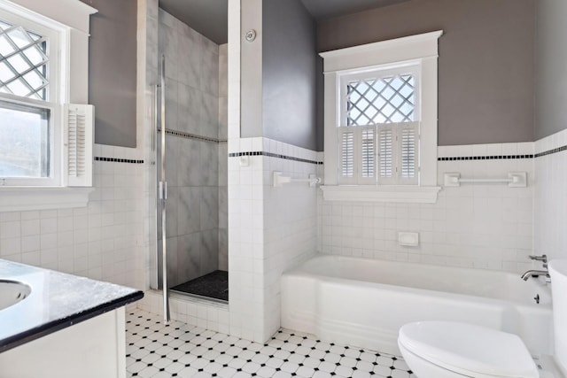 full bathroom with toilet, vanity, plenty of natural light, and tile walls