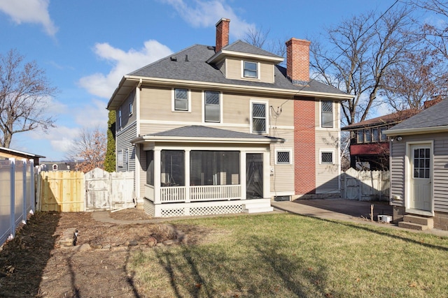 rear view of house featuring a sunroom and a lawn