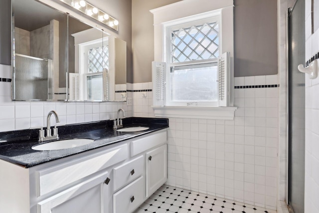 bathroom with vanity, tile patterned floors, tile walls, and a shower with shower door