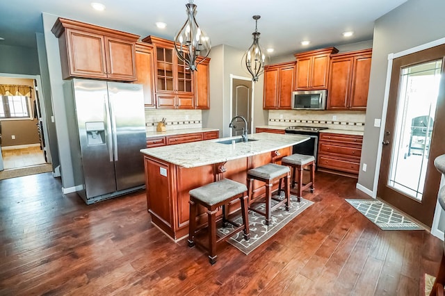 kitchen with dark hardwood / wood-style flooring, a wealth of natural light, a center island with sink, and appliances with stainless steel finishes