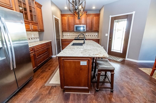 kitchen featuring sink, hanging light fixtures, an island with sink, dark hardwood / wood-style flooring, and stainless steel appliances