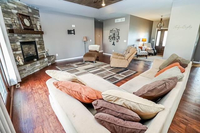 living room featuring dark hardwood / wood-style floors and a stone fireplace