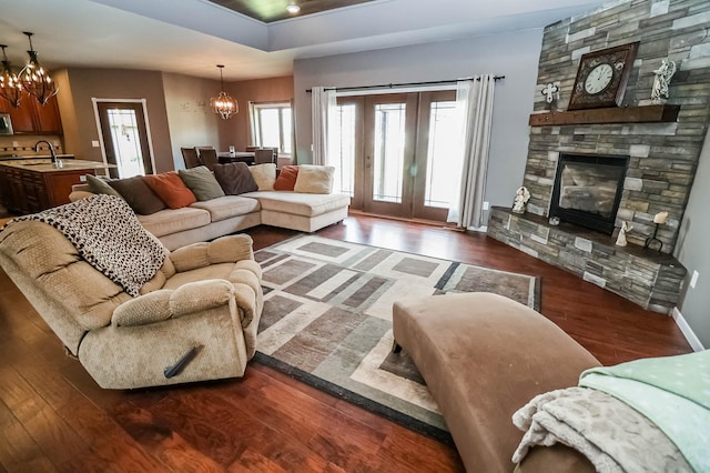 living room with dark hardwood / wood-style flooring, a fireplace, and an inviting chandelier