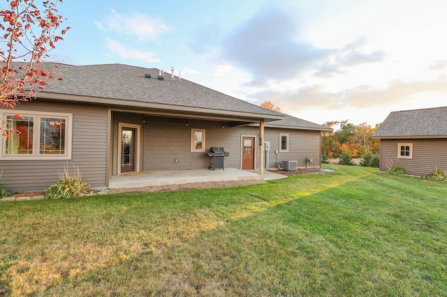 rear view of property with a patio, cooling unit, and a lawn